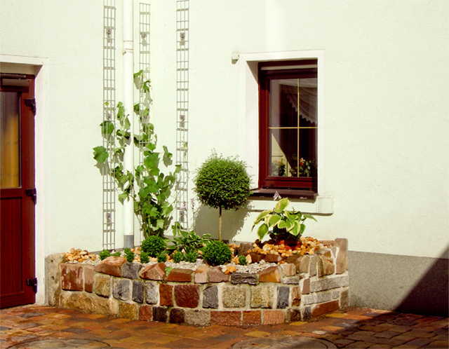 Referenzbild: 39 Innenhofgestaltung, Hochbeet aus einem Natursteinensemble in Kombination mit einer Fasadenbegrünung.